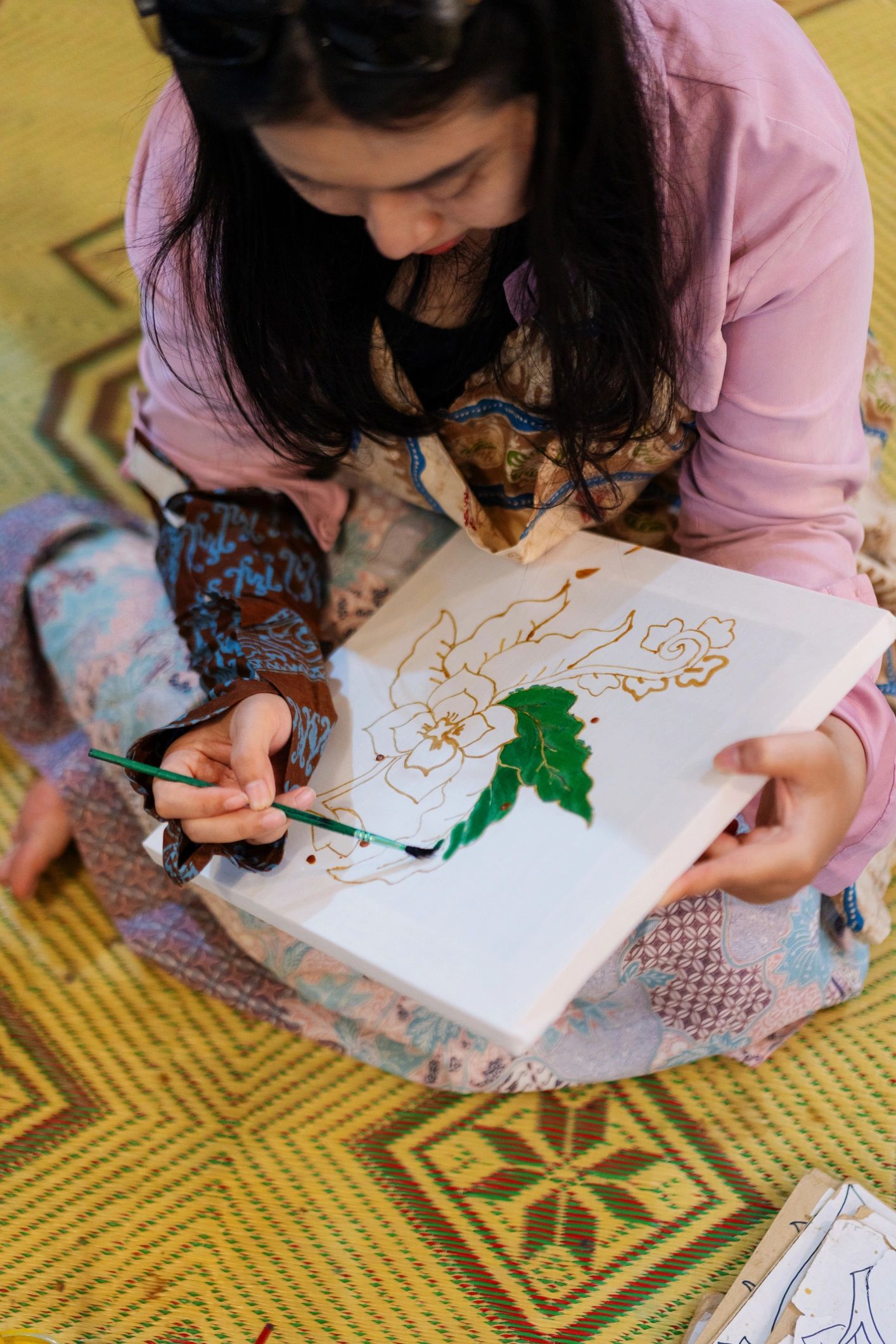 Artist hand-painting a botanical design in green dye